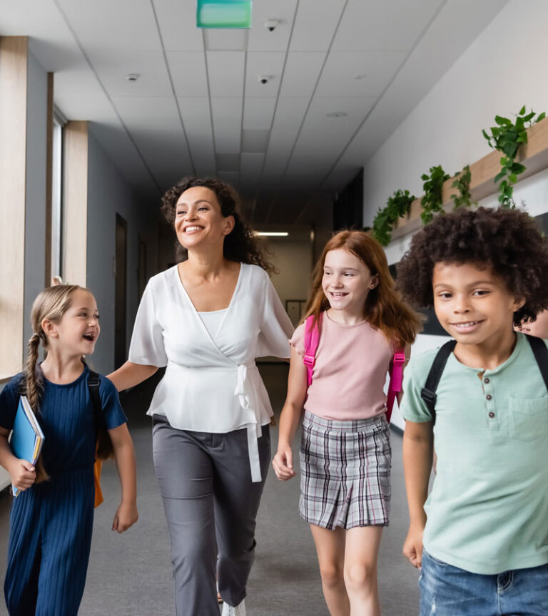 Teacher walks down a school hallway with kids in Brookewater, a master-planned community.