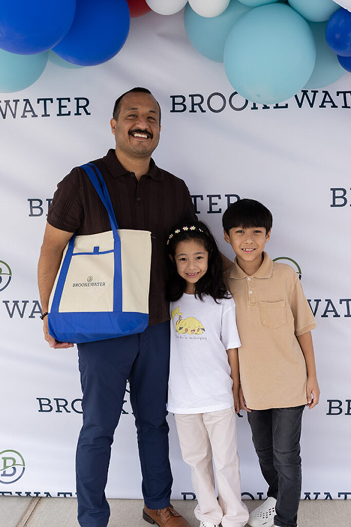 Man and two children pose at Brookewater, a master-planned community, with blue and white balloons.
