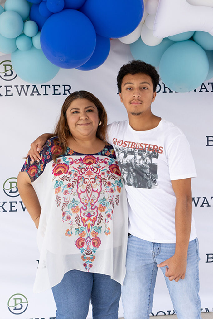 Two people pose together near Richmond TX in front of a step-and-repeat and blue balloon decorations.