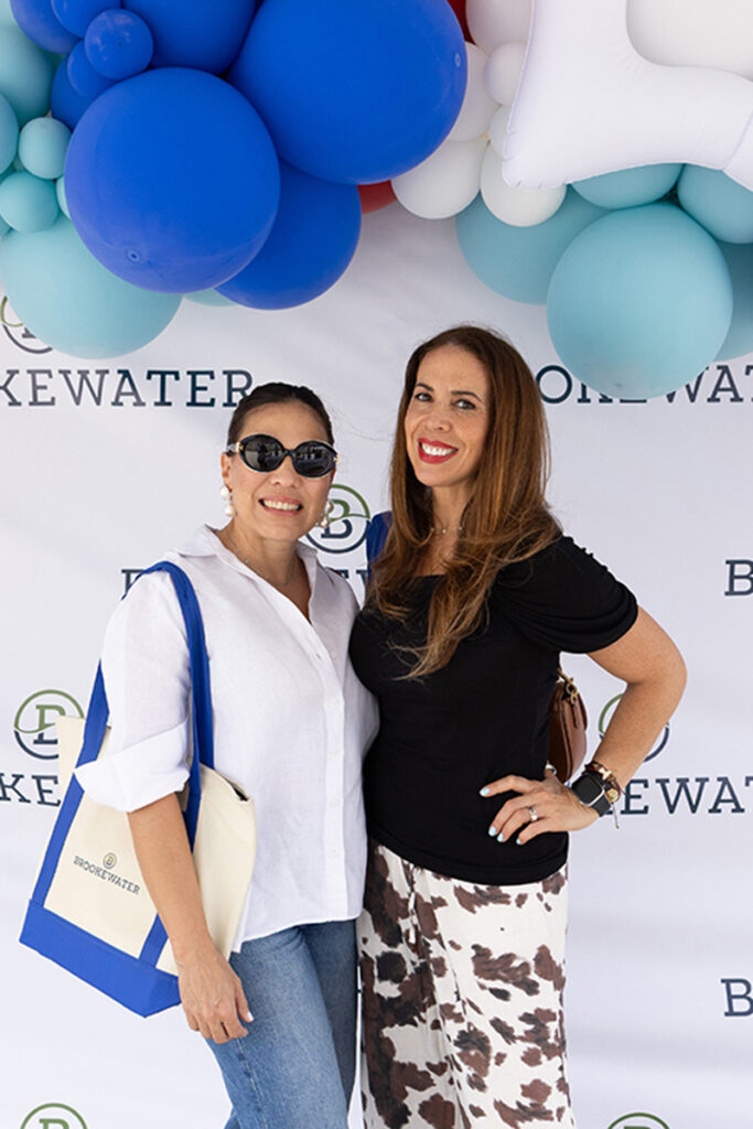 Two women smile by a balloon arch at a Brookewater event near Richmond TX.