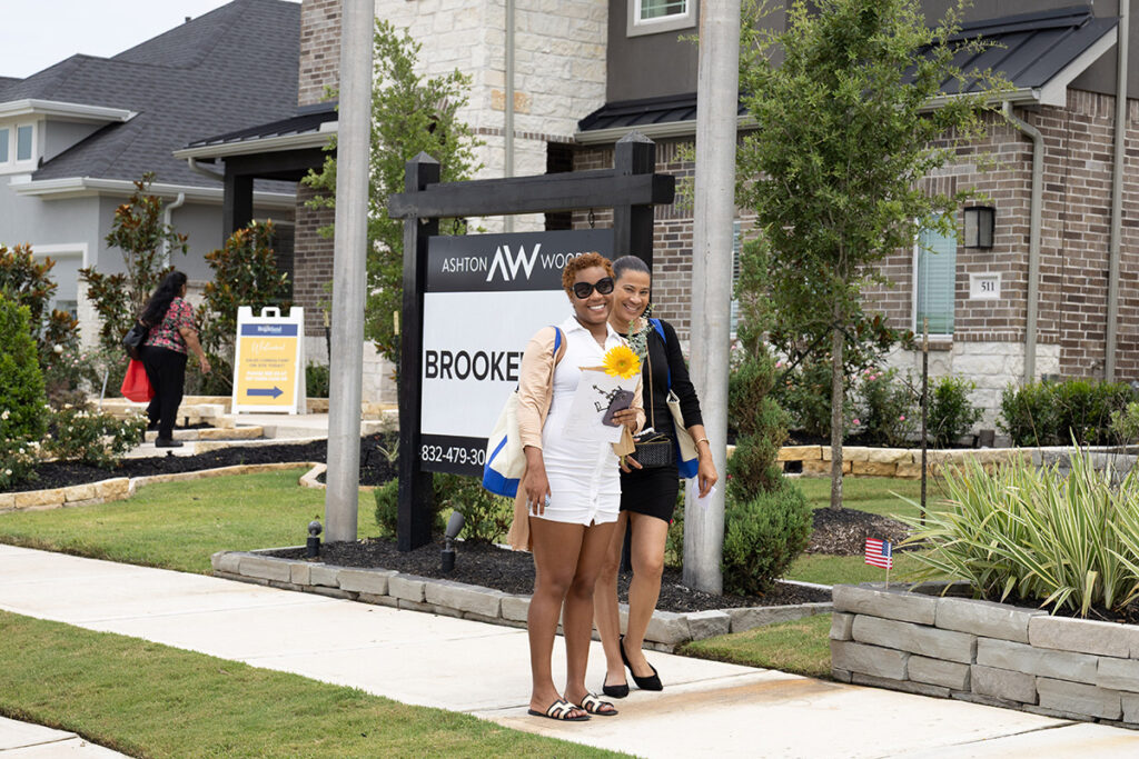 Two women walk near a Brookewater model home sign in a suburb near Richmond TX.