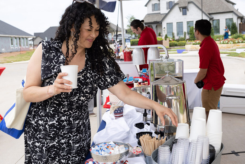 Woman serving herself a drink at an outdoor table in a master-planned community near Richmond TX. Brookewater event.