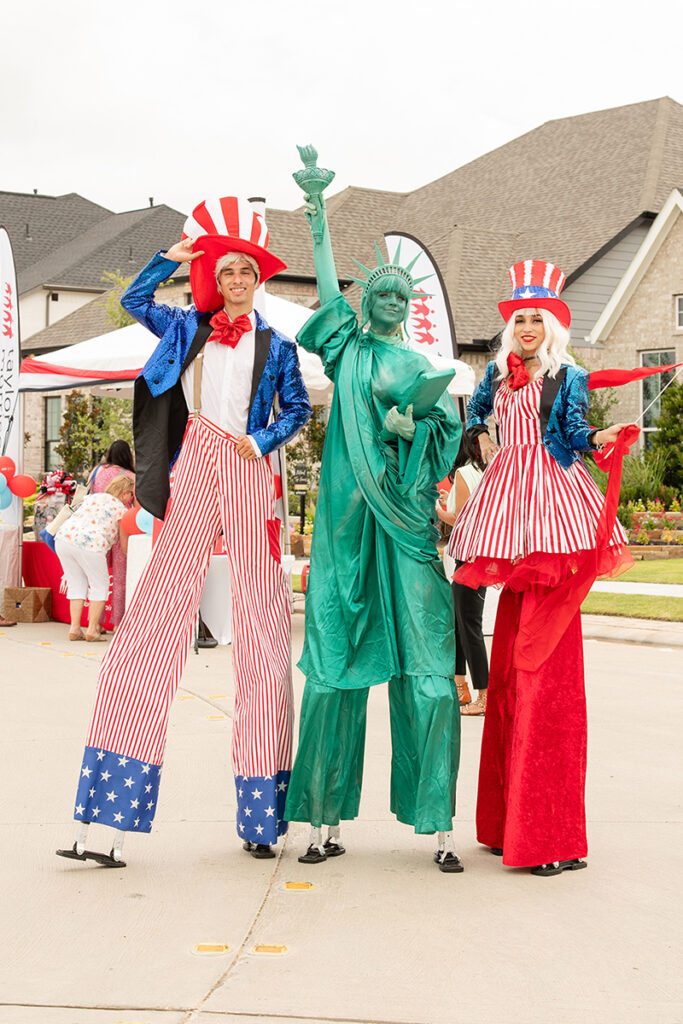 A man poses with stilt walkers and a Statue of Liberty near new Brookewater homes for sale in Richmond TX.