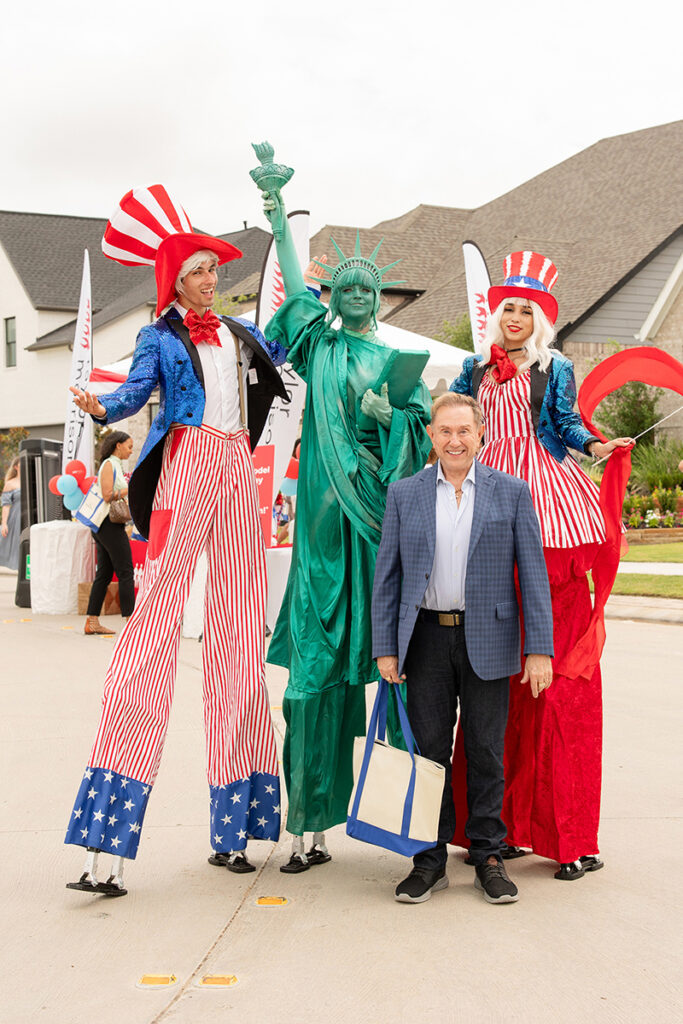 A man poses at a Brookewater event with Uncle Sam and the Statue of Liberty lookalikes.