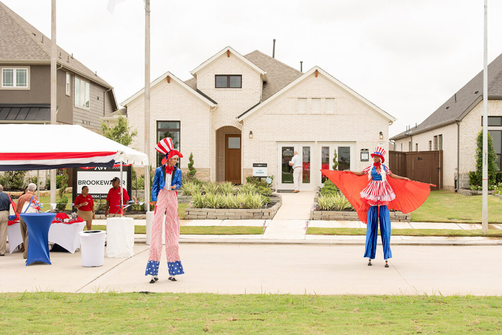 Two people on stilts in patriotic costumes greet guests at Brookewater’s master-planned community.