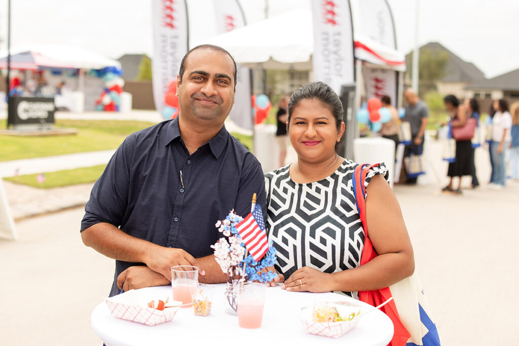 Two people enjoy snacks at an outdoor Brookewater event near Richmond TX with flags.
