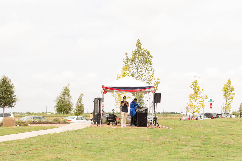 Two people stand under a tent with audio gear in a Brookewater master-planned community near Richmond TX.