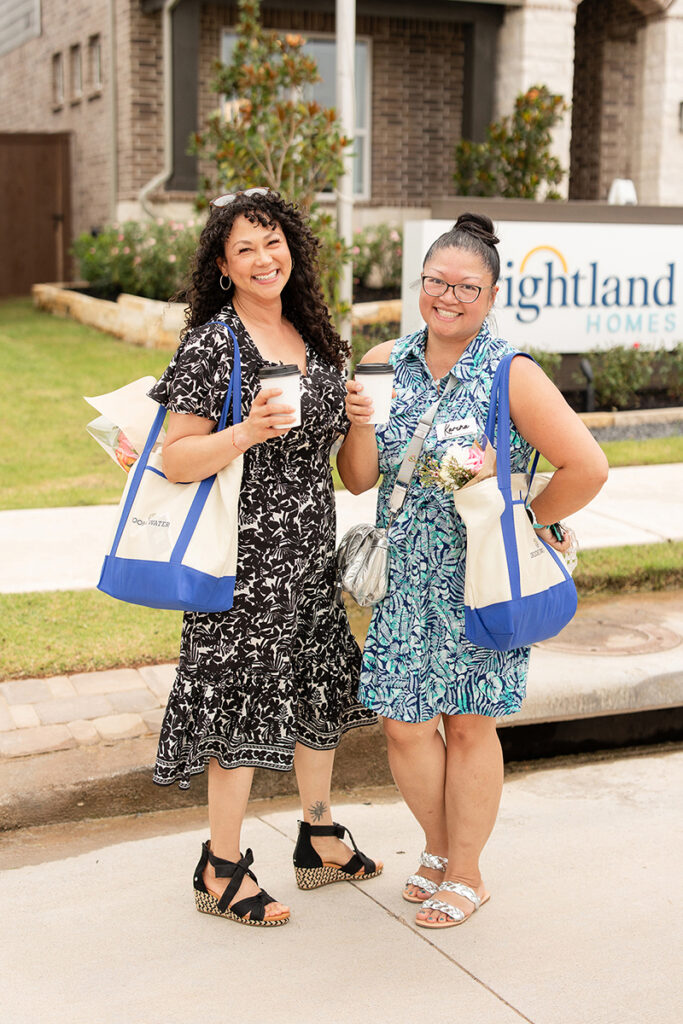 Two women smile outdoors, coffee in hand, near new homes for sale in Brookewater, a master-planned community.