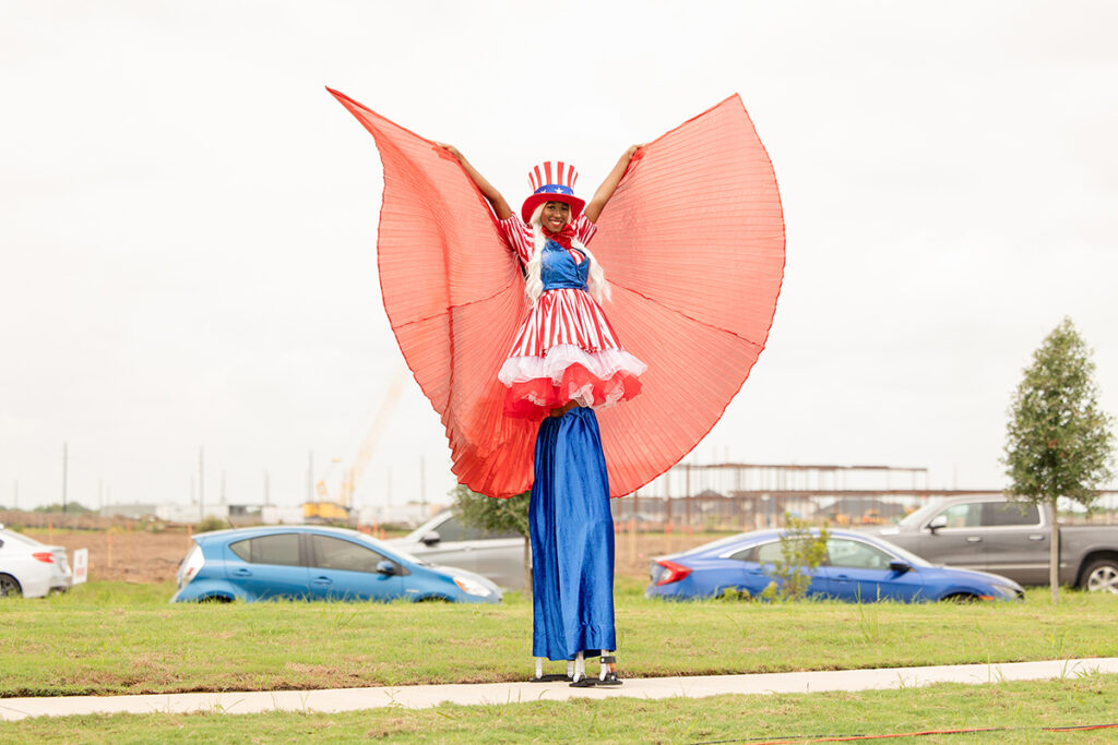 Person on stilts in red, white, and blue costume delights in a Brookewater master-planned community near Richmond TX.