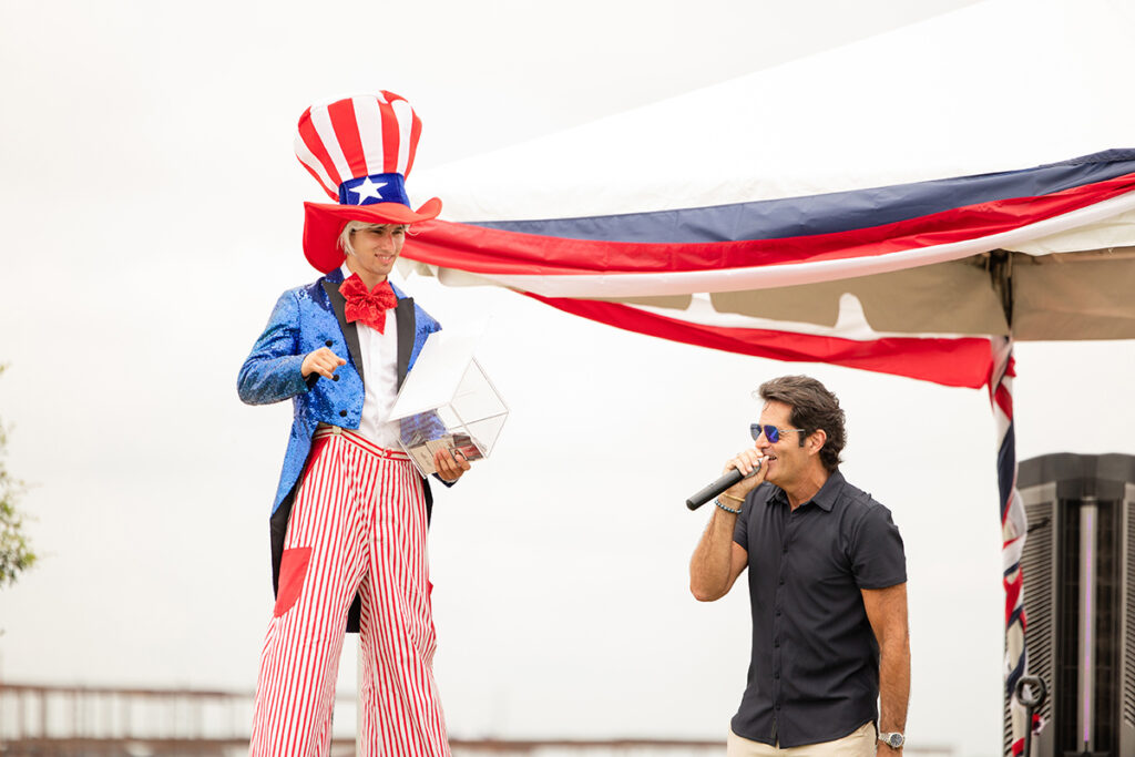 A man dressed as Uncle Sam stands beside another at a master-planned community Brookewater event outdoors.