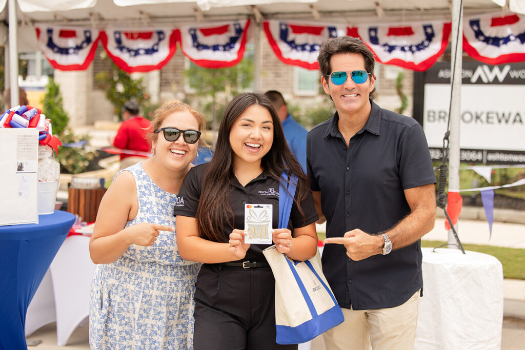 Three people smile and point at an award at Brookewater near Richmond TX’s new home builders event.