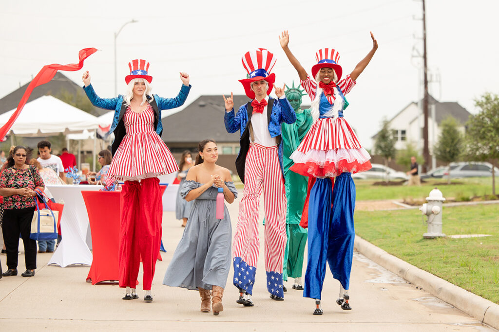 Three people on stilts in patriotic costumes walk at a Brookewater event near Richmond TX.