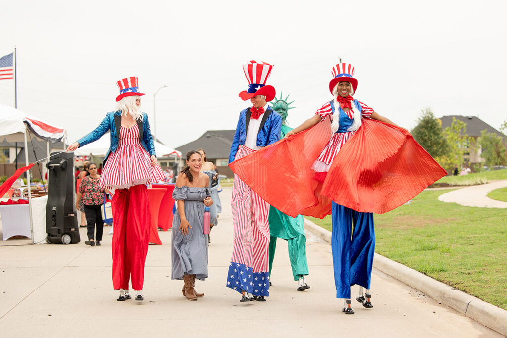 Four on stilts in patriotic attire at Brookewater, a vibrant master-planned community event.