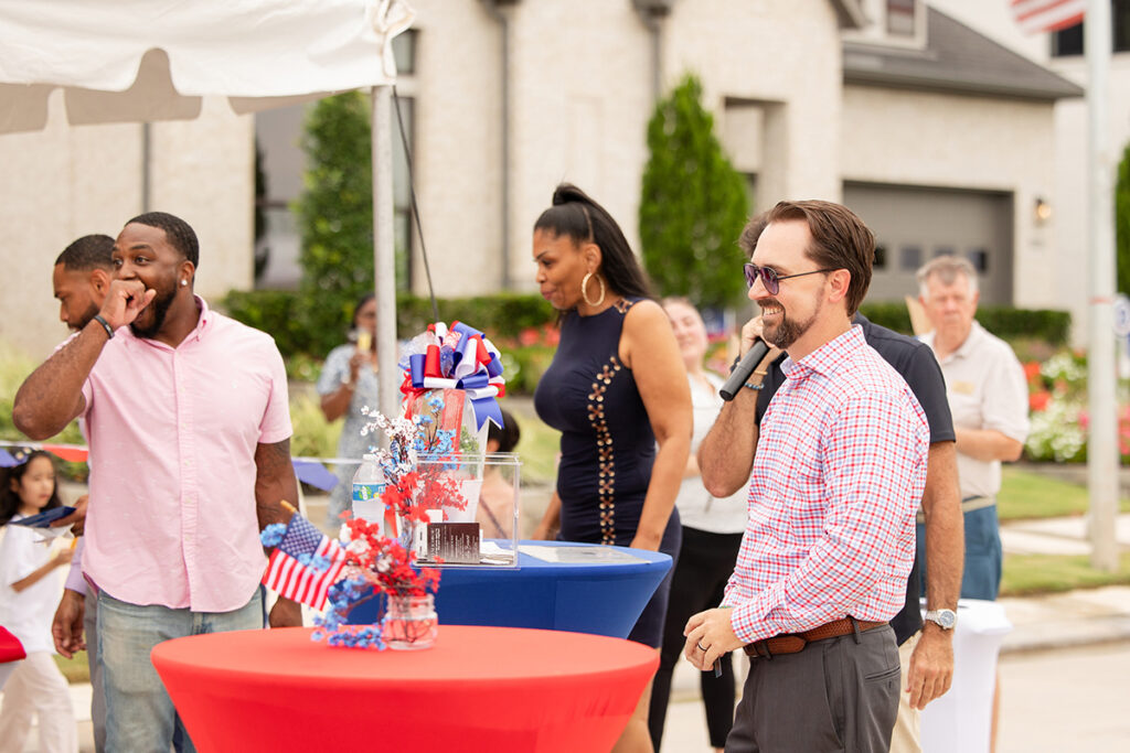 People socializing outdoor Brookewater event near Richmond TX by decorated tables with patriotic-themed centerpieces.