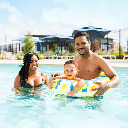 Two adults and a child enjoy Brookewater’s sunny pool, near Richmond TX.