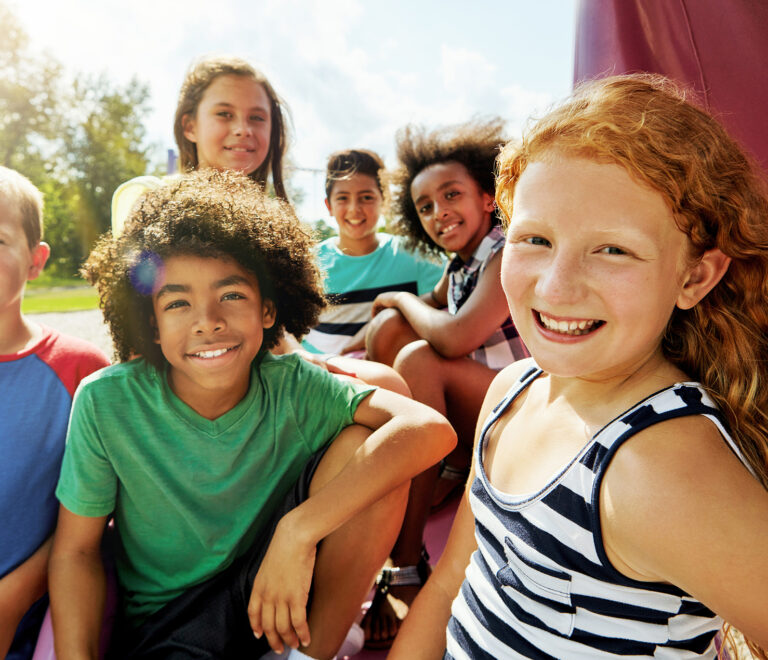 A group of children smiling outdoors in the Brookewater master-planned community.
