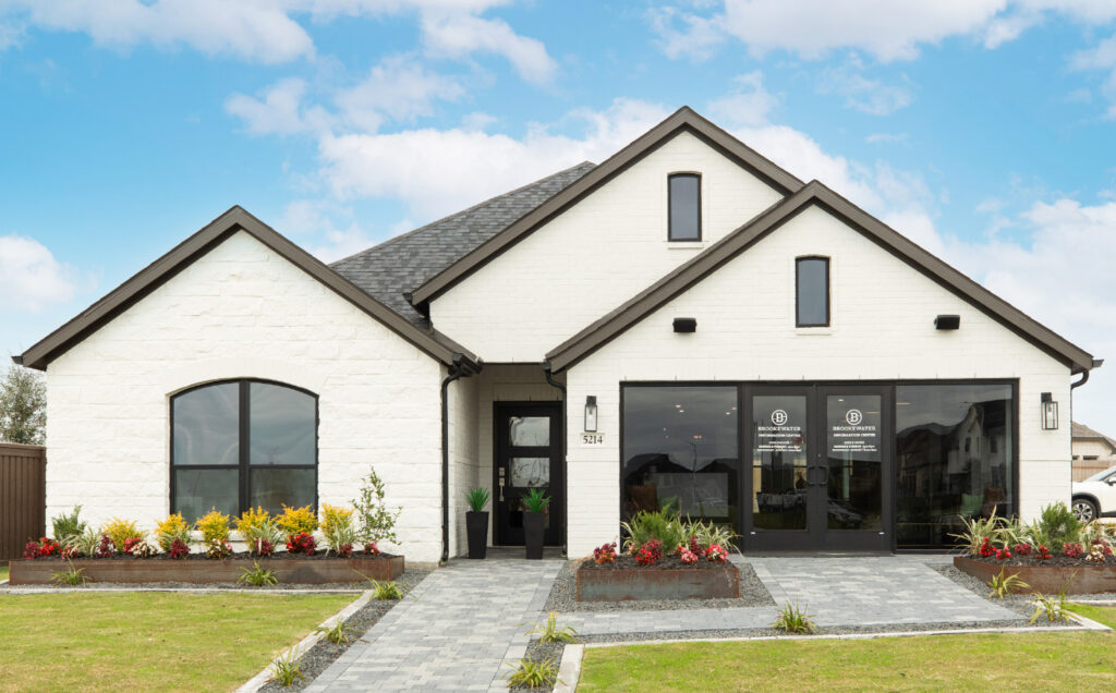 Modern white brick house with black trim, large windows, and landscaped front yard.