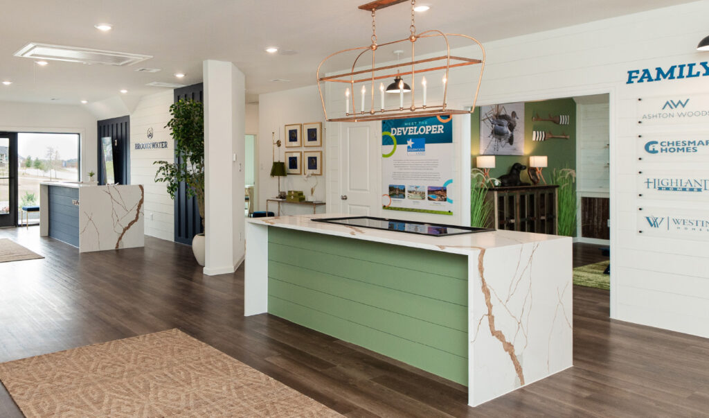Modern sales office lobby with two white reception desks and wood flooring.