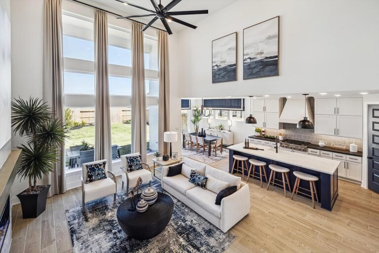 Modern open-concept living room and kitchen with tall windows and neutral decor.