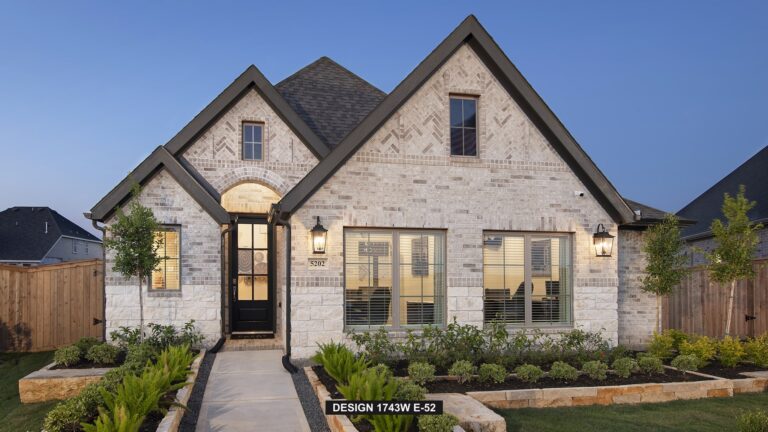 Single-story brick house with dark roof, front garden, and large windows at dusk.